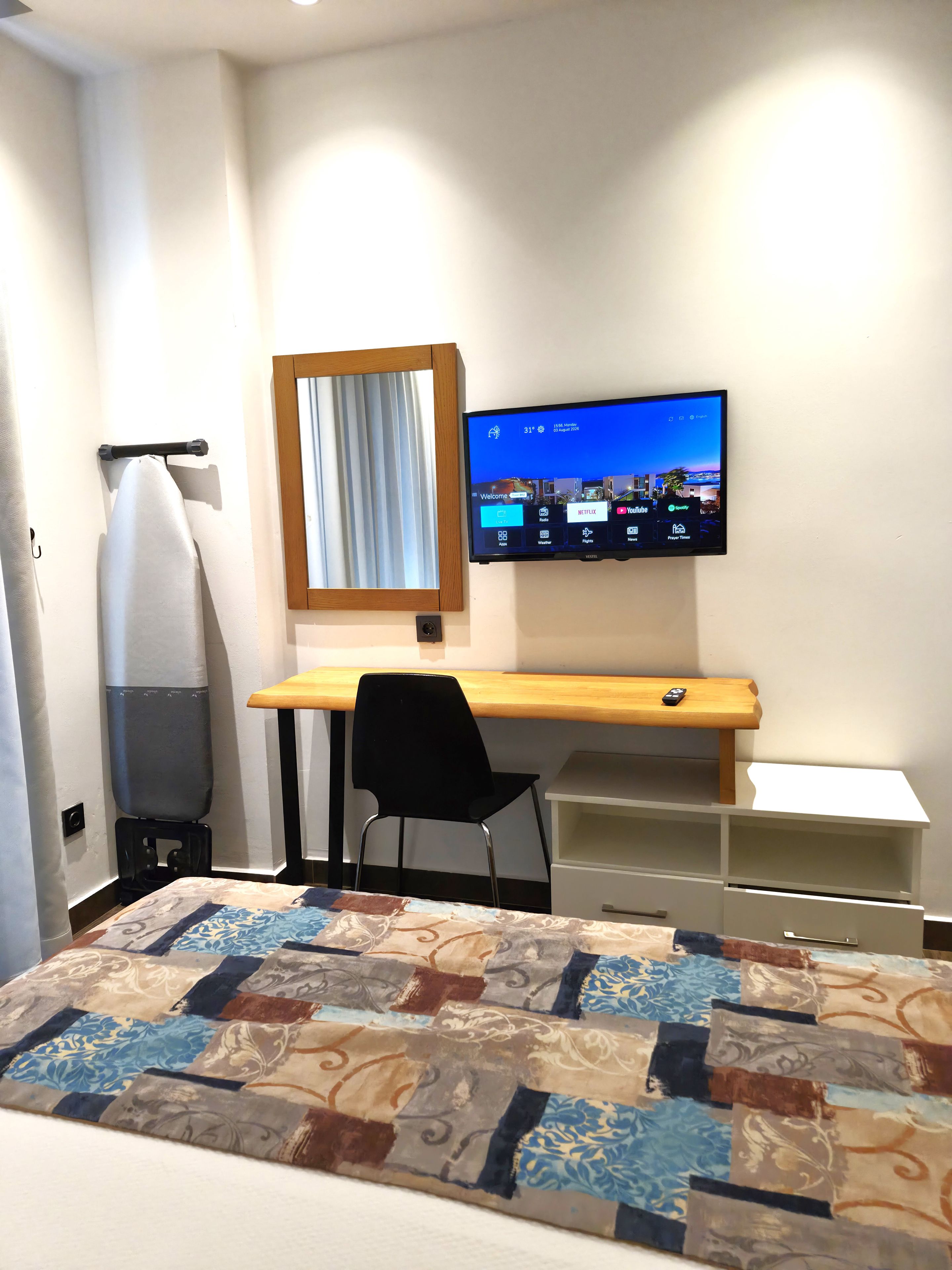 A hotel room with a bed, a desk, a chair, a television, and a window with curtains.