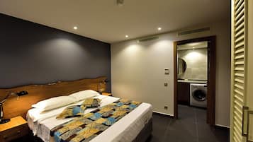 Une chambre d’hôtel équipée d’un lit, d’une table de chevet, d’un bureau, d’une machine à laver et d’un miroir.