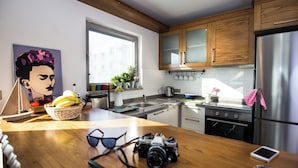 A modern kitchen with wooden cabinets, a stainless steel refrigerator, and a window providing natural light. - Degirmenburnu Residence (Bodrum)