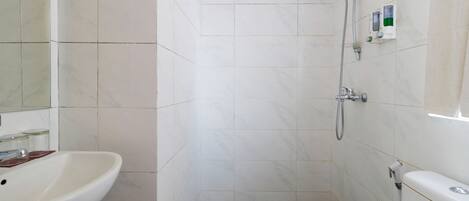 Un bagno con un lavandino bianco, una doccia con soffione manuale e un water.