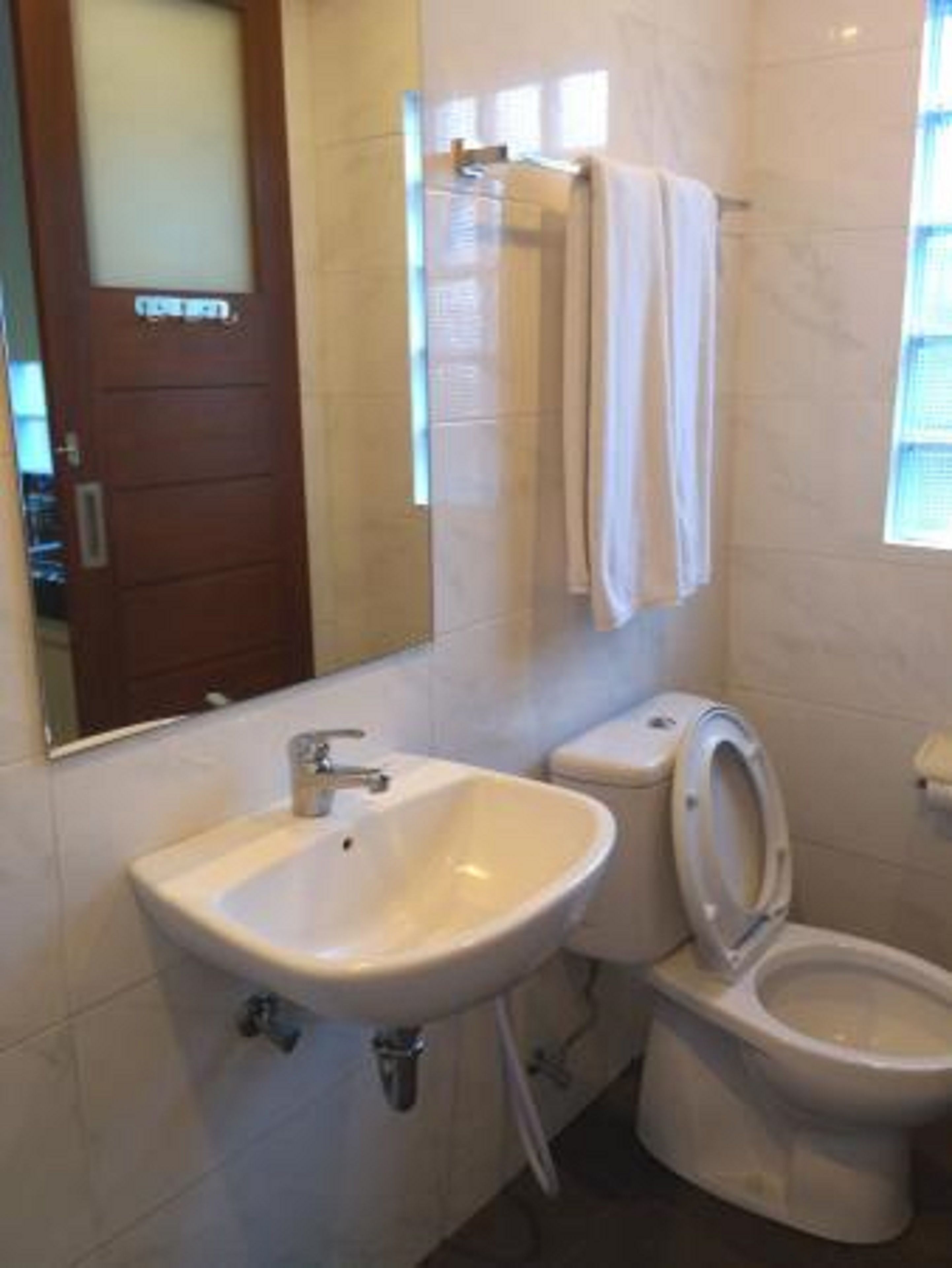 Un baño con lavamanos, inodoro y espejo.