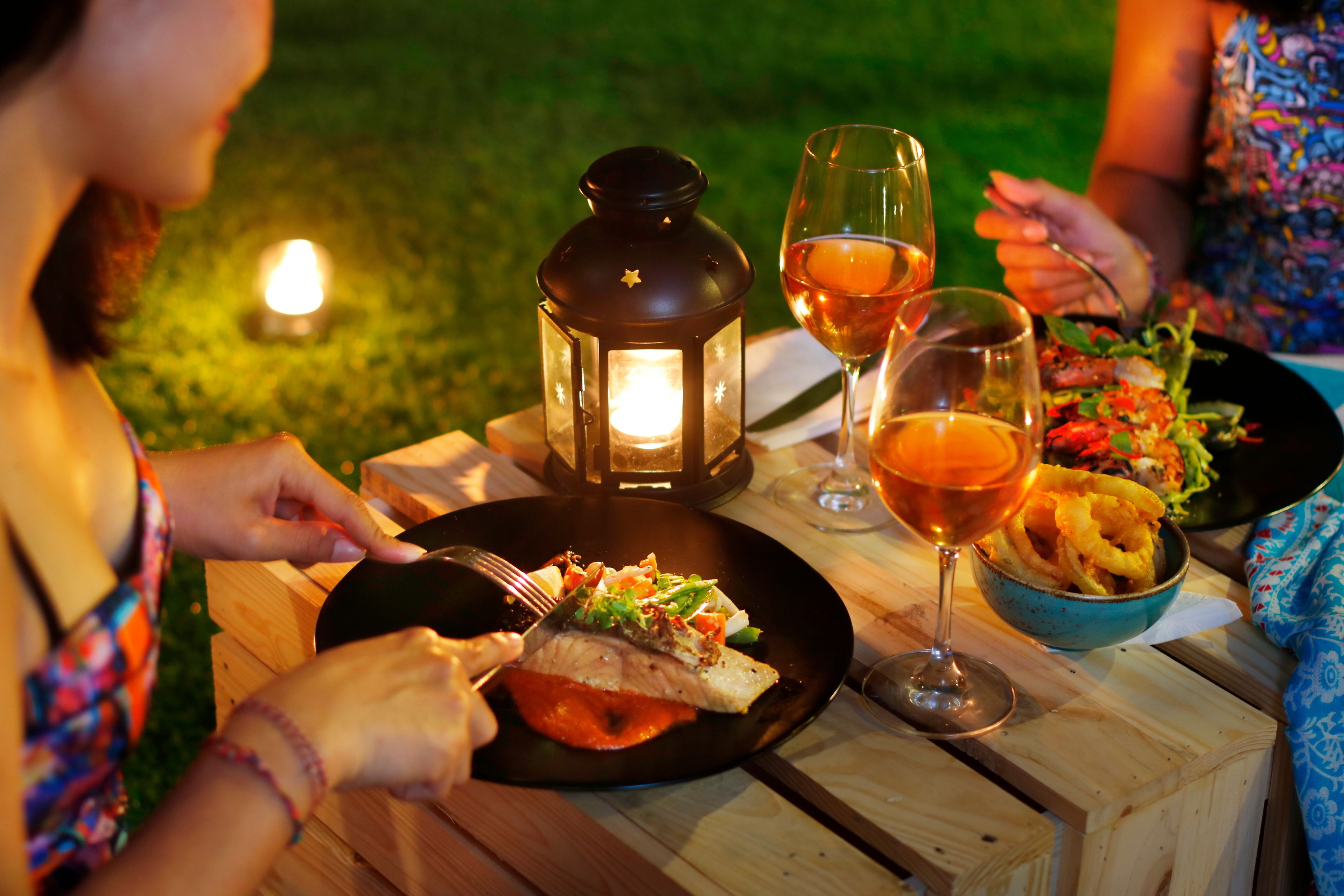 Een houten tafel met een kaars, een glas wijn en een bord eten.