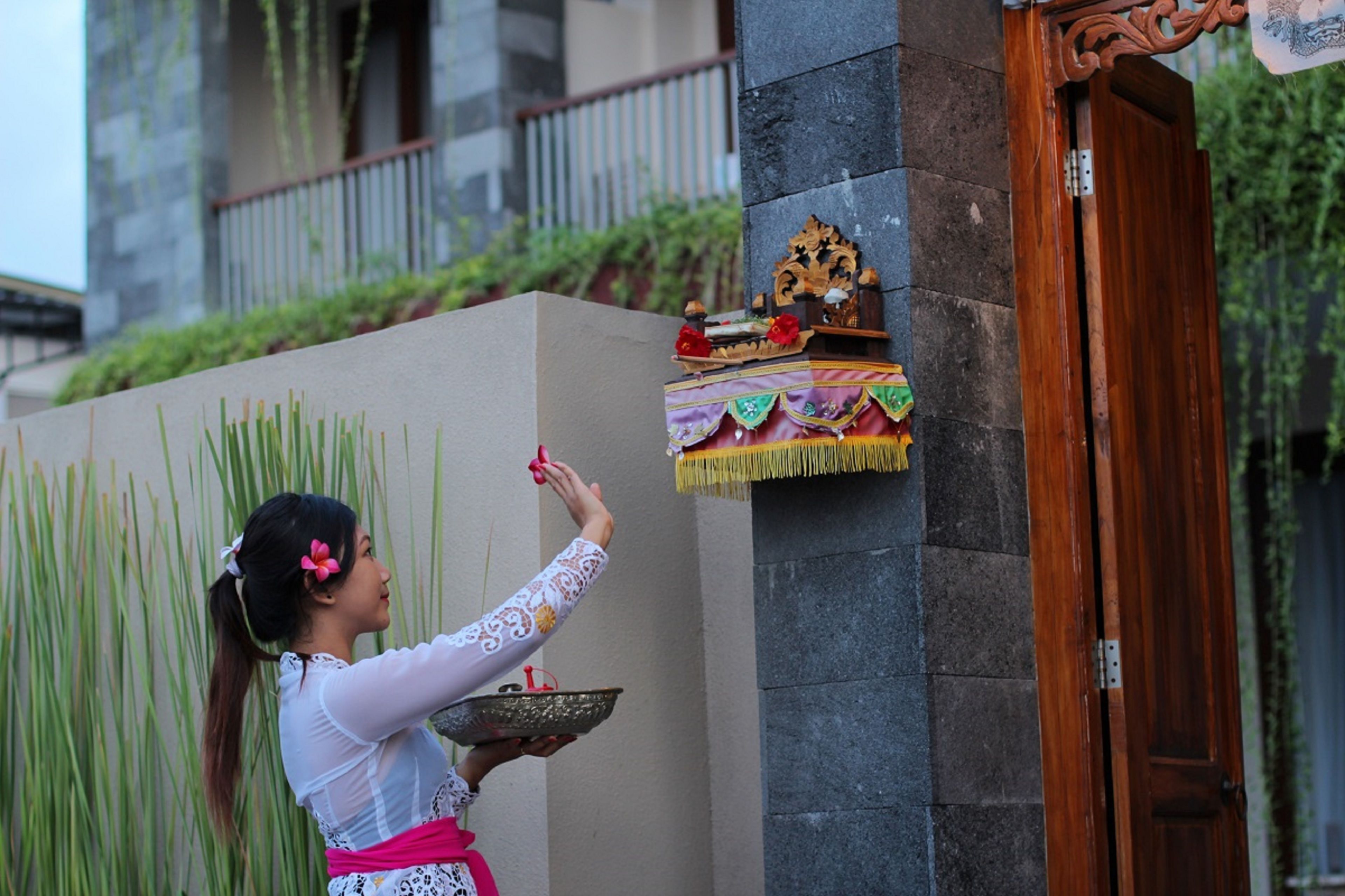A person performing a ritual with offerings at a door.