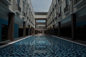 A large indoor swimming pool with a checkered tile floor, surrounded by multiple balconies with black railings. - Temasek Hotel (Malacca City)