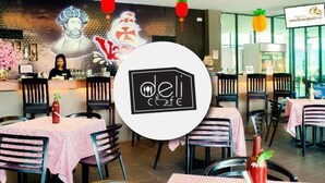 A restaurant interior with tables covered in checkered tablecloths, a central logo, and a mural on the wall. - Temasek Hotel (Malacca City)
