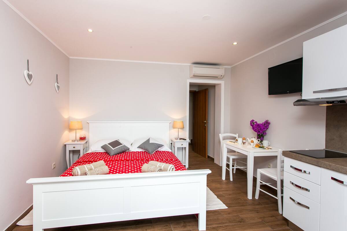 Une chambre à coucher avec un lit blanc, une couvre-lit à pois rouges et un bureau blanc avec une chaise.
