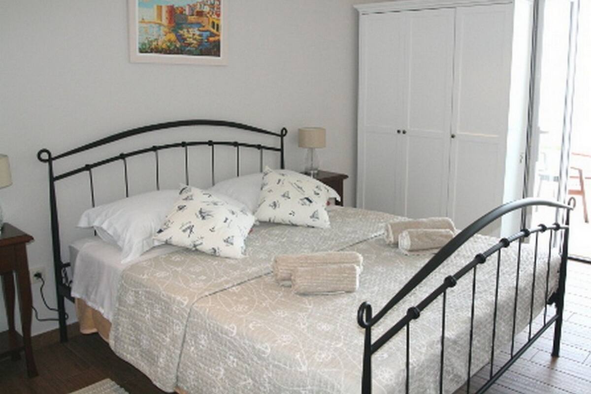 Une chambre à coucher avec un lit, une table de chevet, une lampe, une armoire et un tableau au mur.