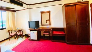 A hotel room with a desk, chair, television, wardrobe, and a red carpet. - Crystal Hotel Krabi (Krabi)