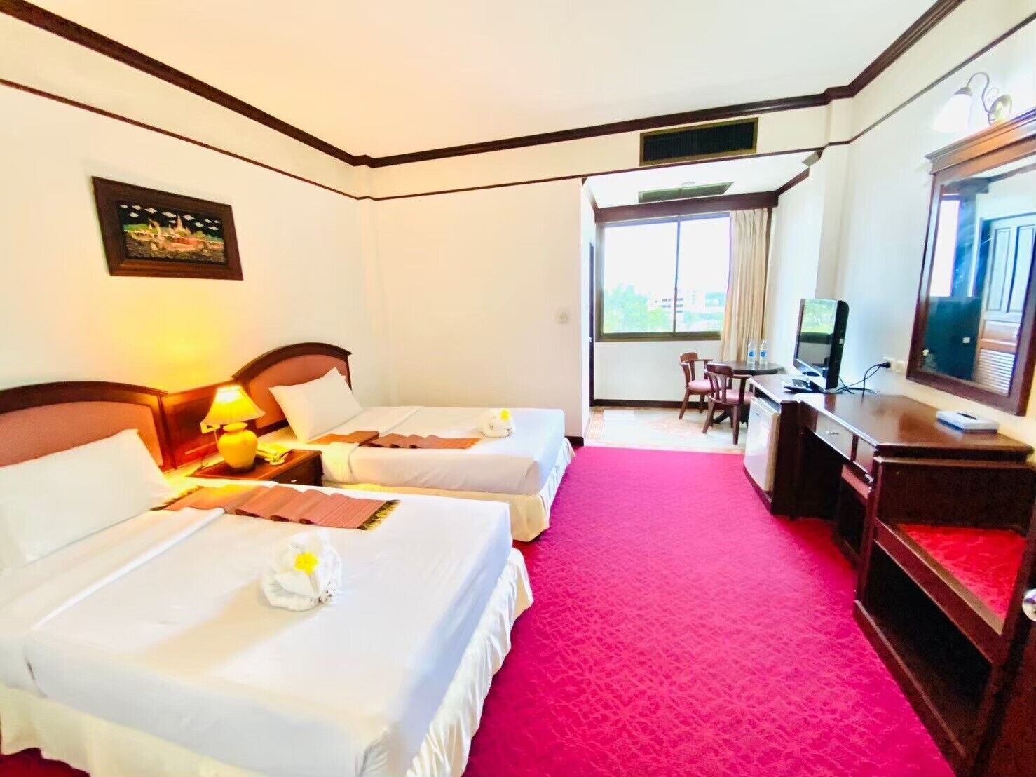 A hotel room with two beds, a desk with a computer, and a TV.