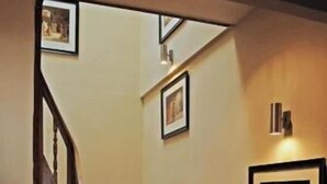 Una escalera de madera con barandilla, flanqueada por cuadros en las paredes.
