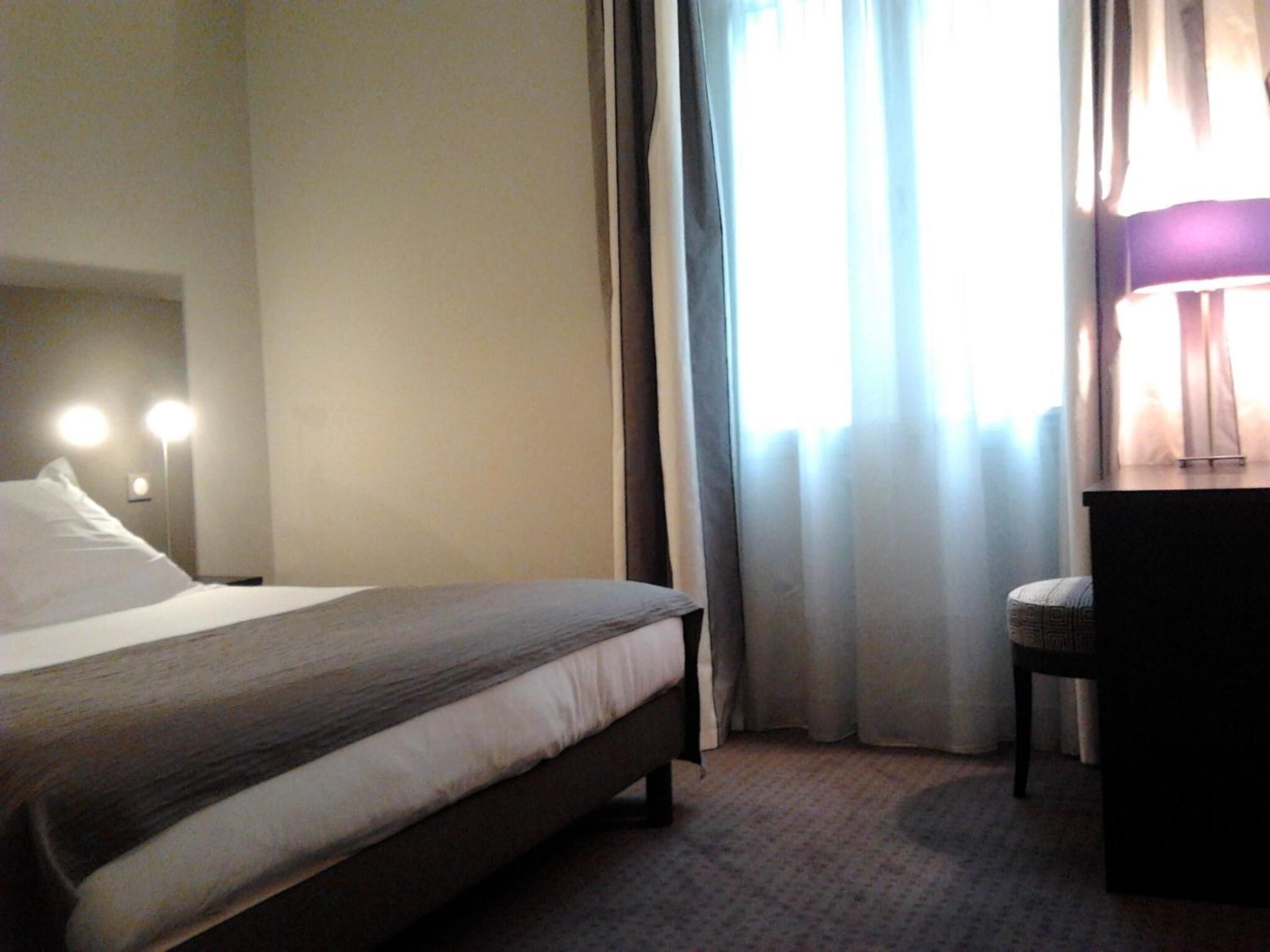 A hotel room with a bed, a desk, and a chair.