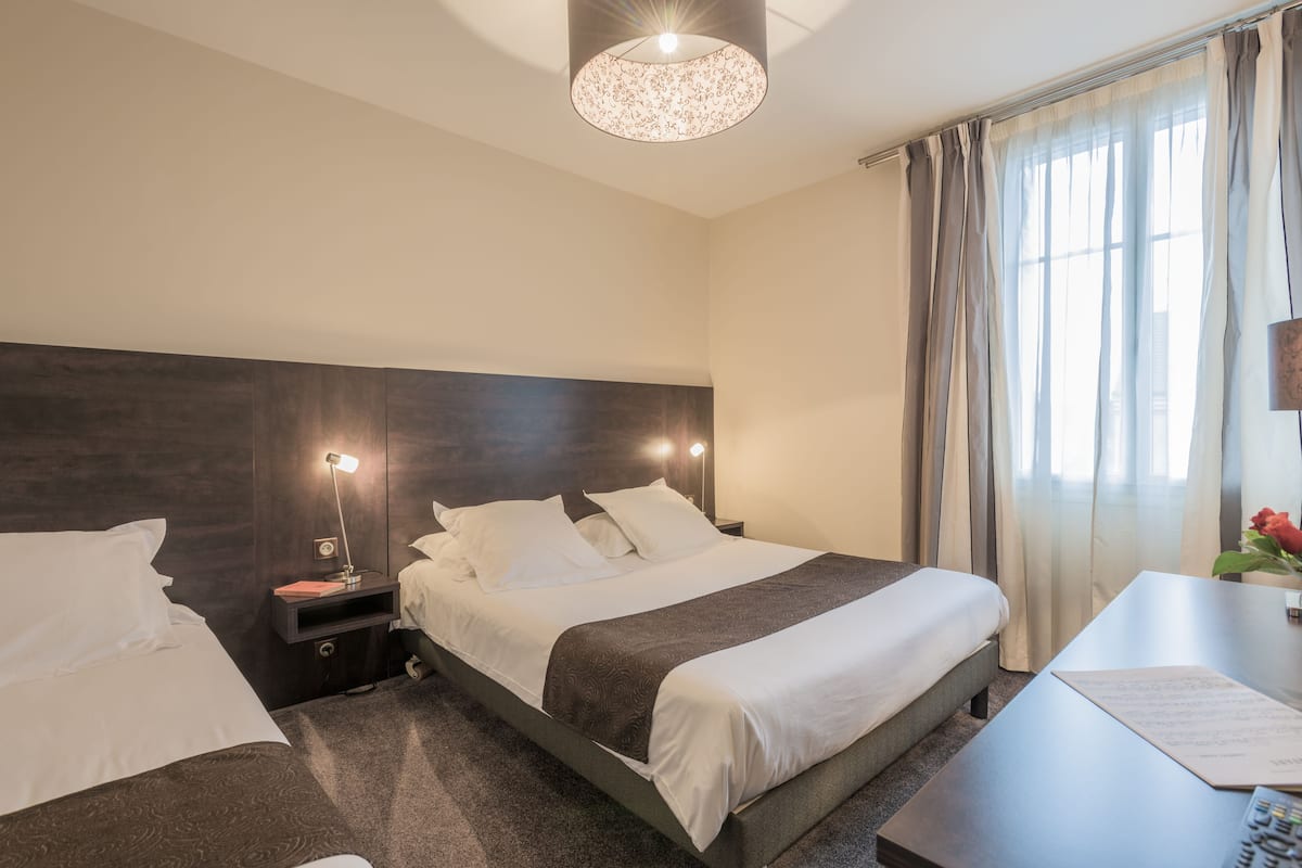 Une chambre d’hôtel moderne avec un grand lit, des tables de chevet, un bureau et une fenêtre avec des rideaux.