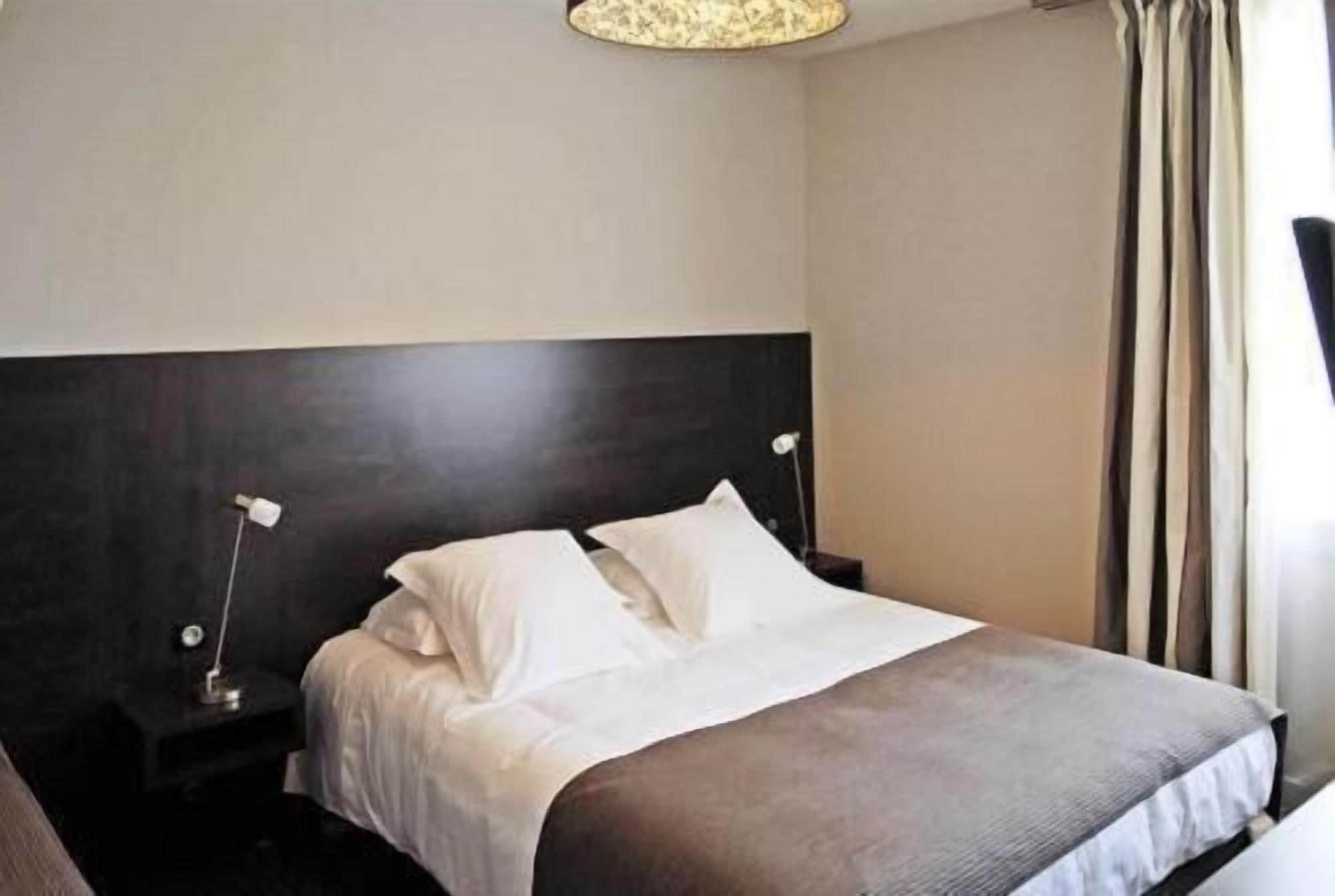 Una habitación de hotel con una cama grande, dos mesitas de noche y un cabecero moderno.