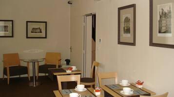A dining area with tables, chairs, and framed pictures on the walls.