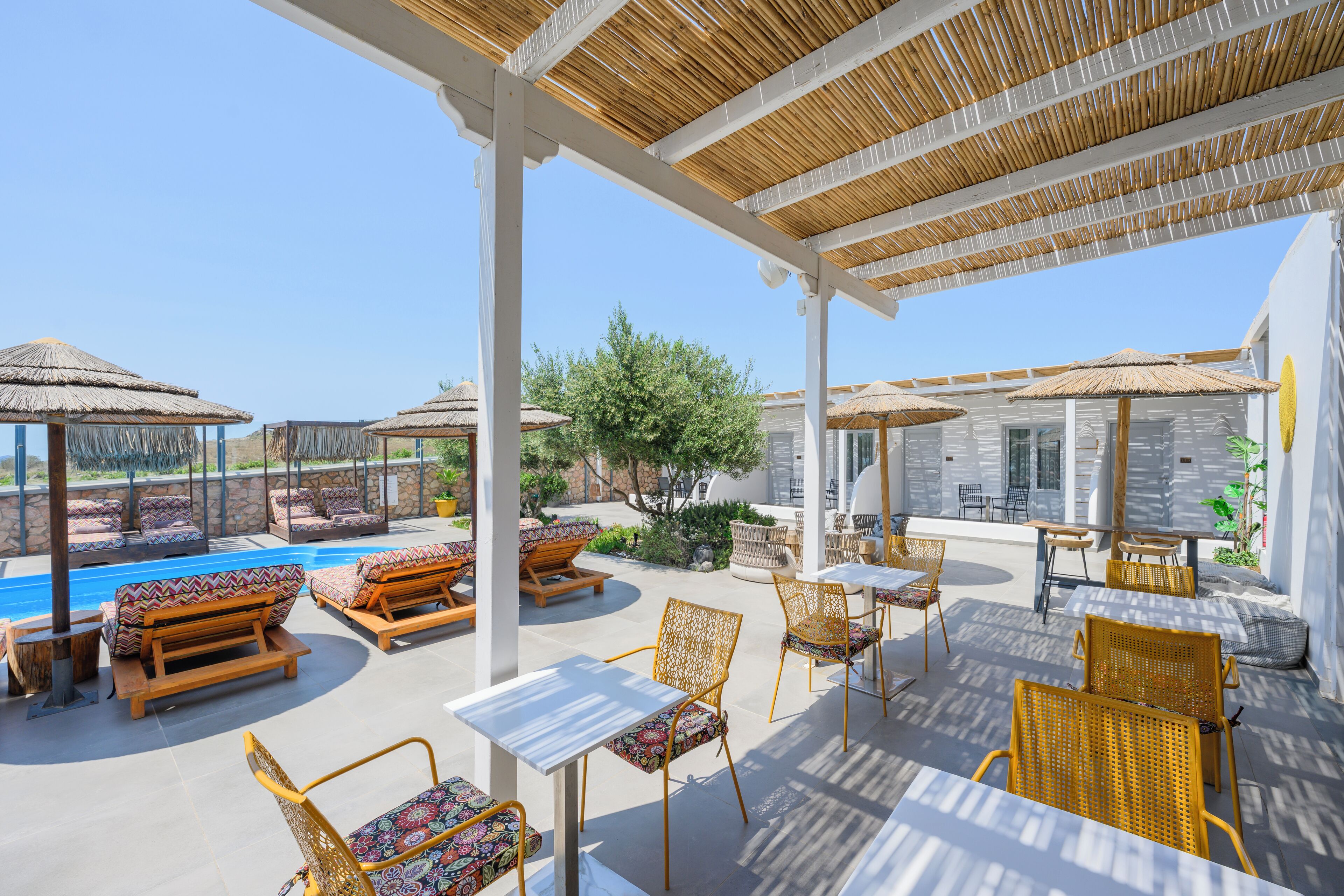 A covered outdoor area with seating, a pool, and umbrellas.