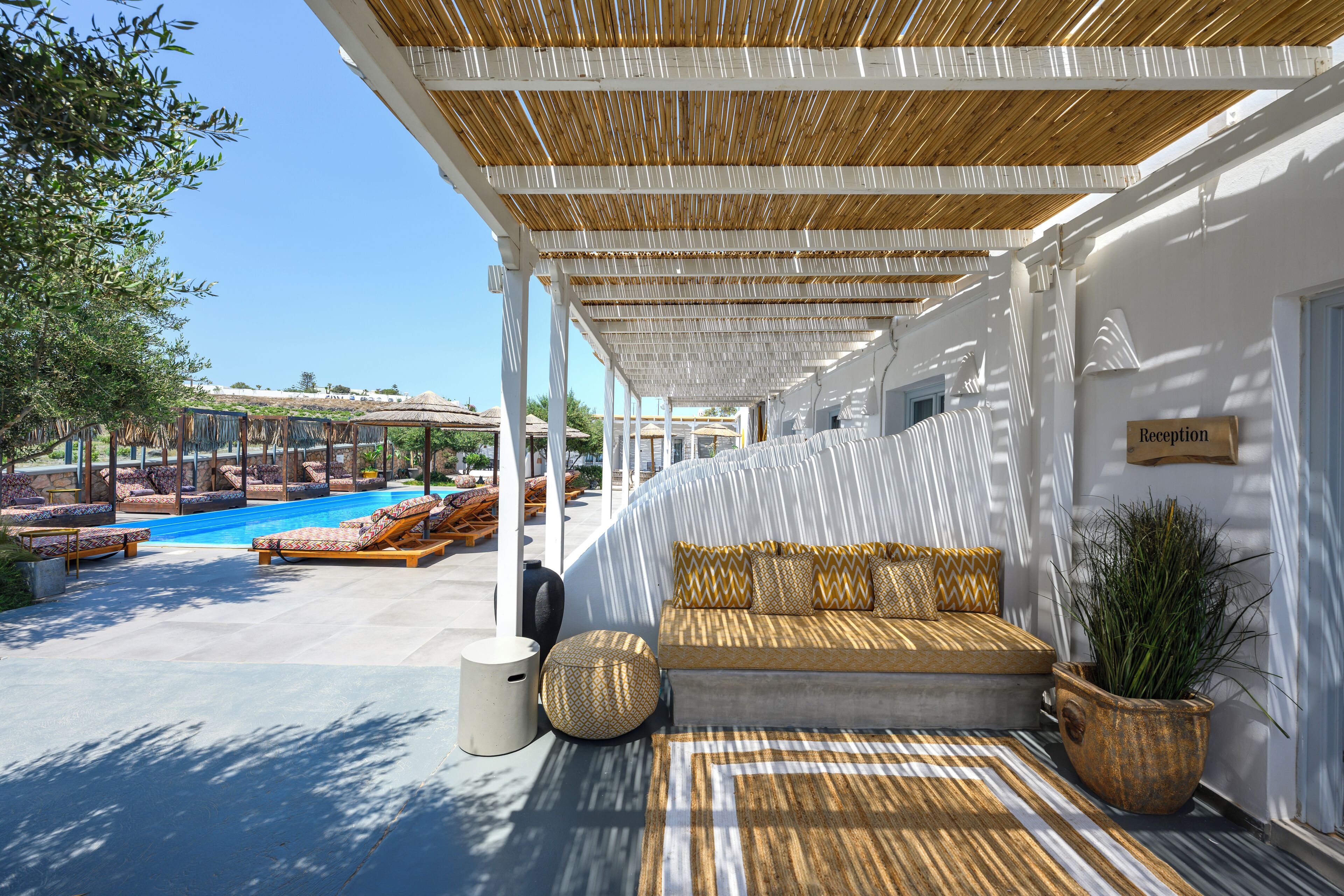 A covered outdoor seating area with a pool, white walls, and a reception sign.