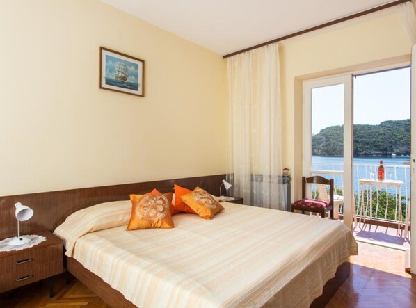 Habitación de hotel con cama, mesita de noche, escritorio y vista a un balcón con mesa y sillas.