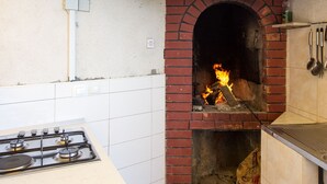 A kitchen with a gas stove, a brick oven, and a tiled backsplash. - Villa Malfi (Dubrovnik)