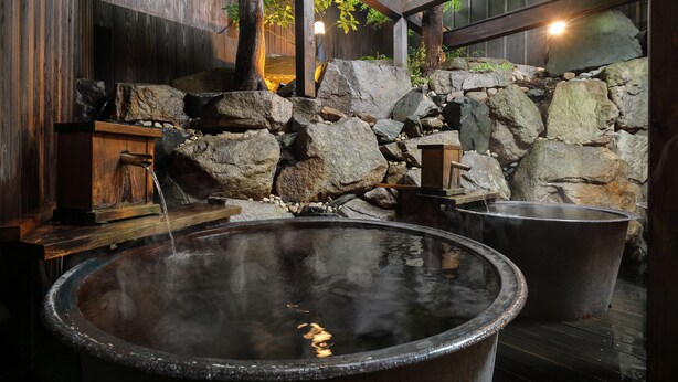 Un espace de bain traditionnel en pierre, avec des bancs en bois et un mur en pierre rustique.