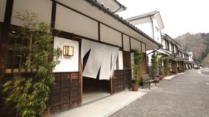Un bâtiment japonais traditionnel doté de tatamis au sol, de portes coulissantes en bois et d’une allée couverte.