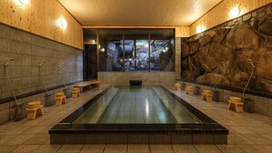 Un sauna avec un intérieur en bois, des murs en pierre et une grande piscine centrale.