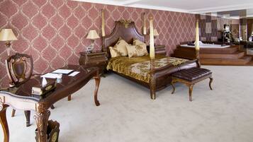 A bedroom with a four-poster bed, a nightstand, a desk, and a chair.