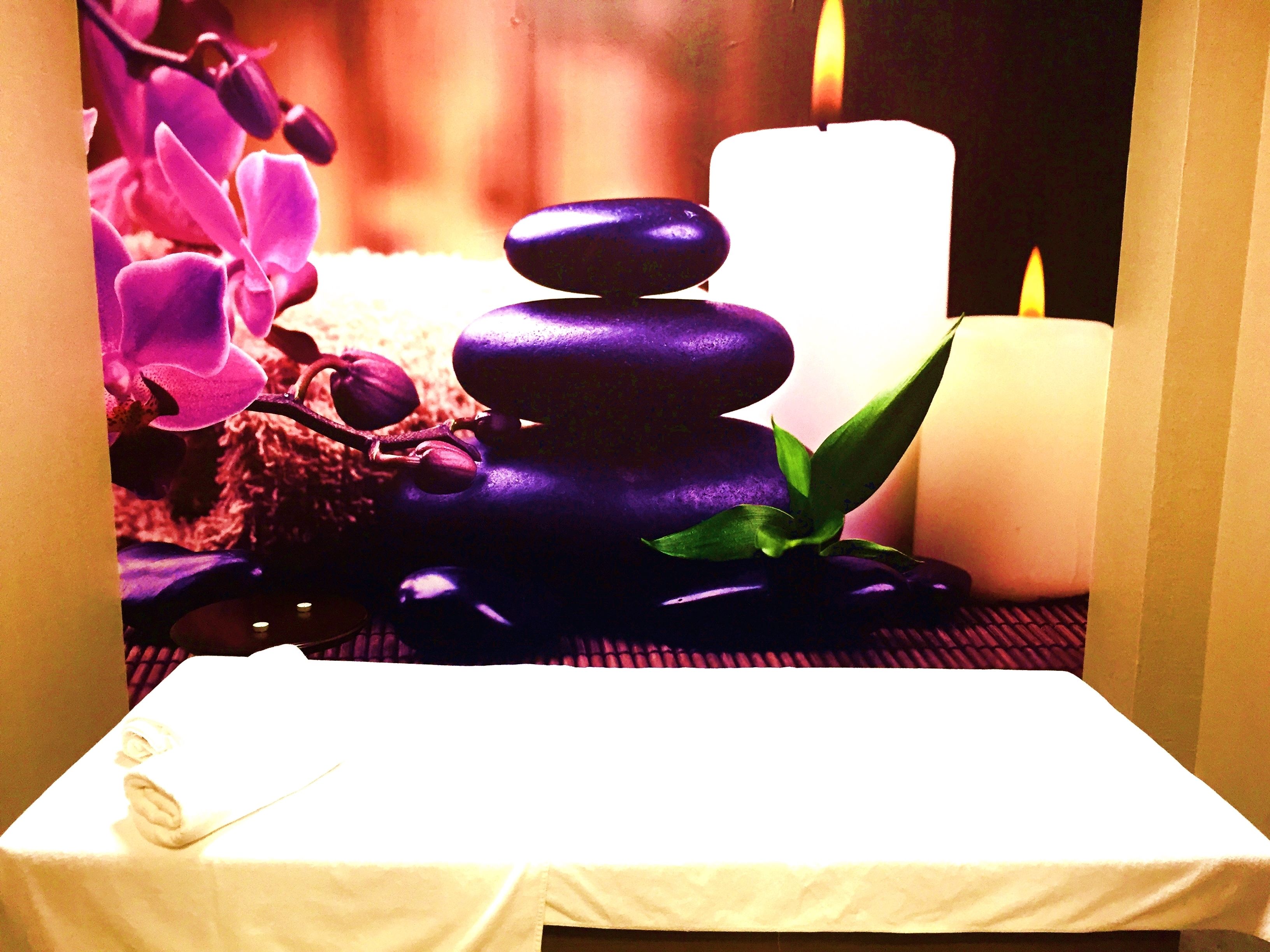 Un área de spa con una composición de piedras, velas y flores moradas.