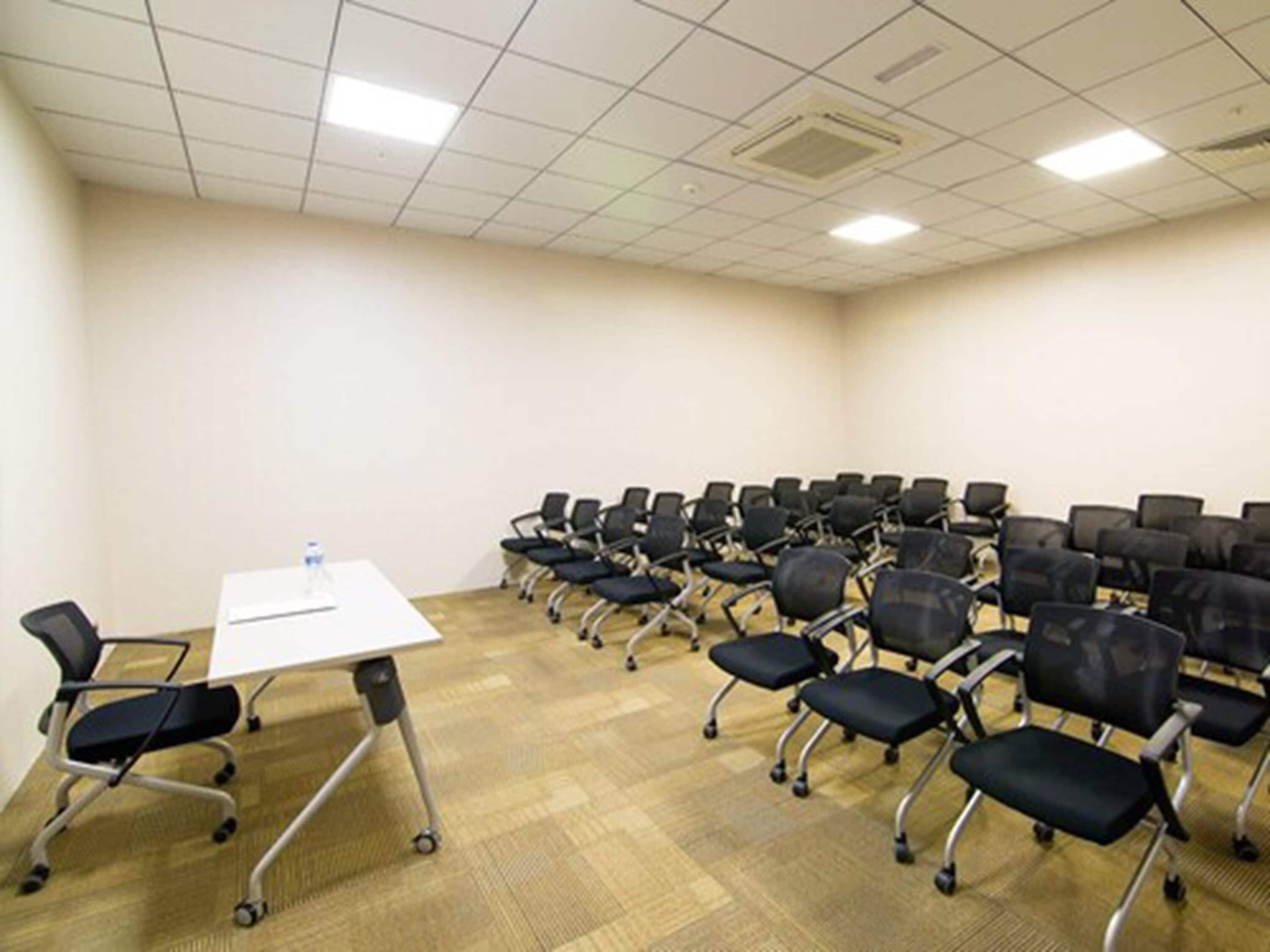 A conference room with a white table, multiple black chairs, and a carpeted floor.
