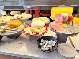 A buffet with various cheeses, meats, and other food items displayed on plates and bowls.
