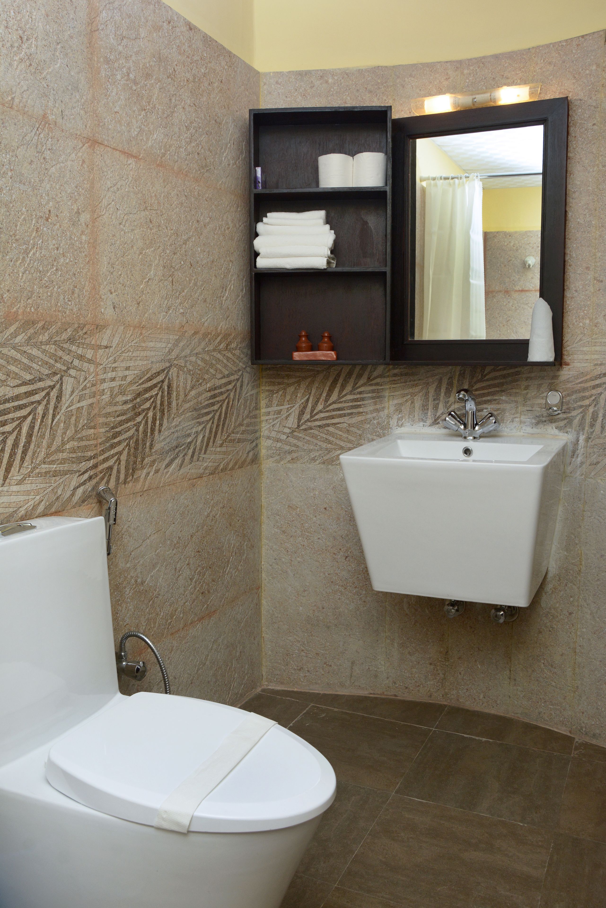 Un baño con inodoro, lavamanos y estante con artículos de tocador.
