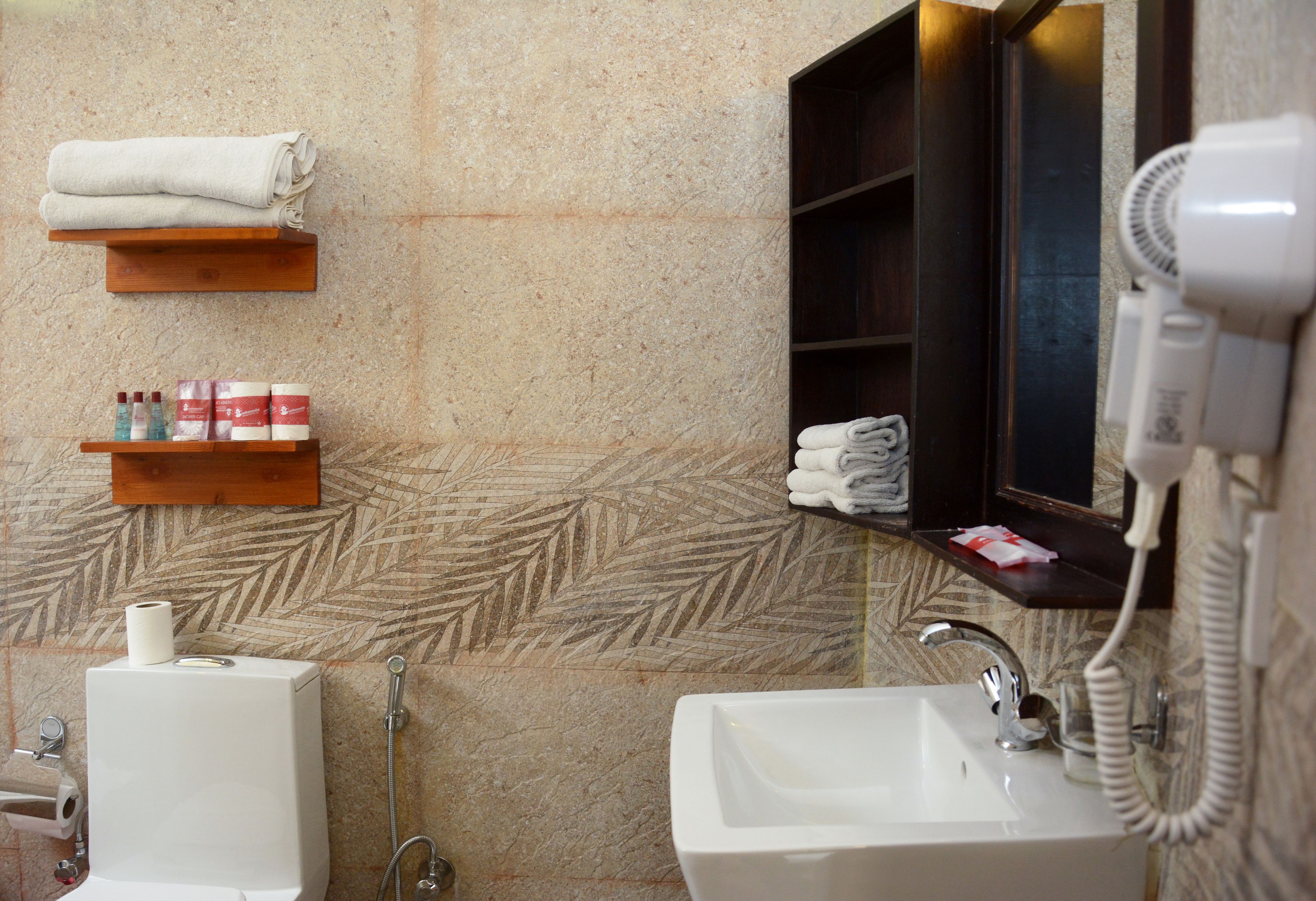 A bathroom with a sink, a toilet, a towel rack, a hairdryer, and a shelf with toiletries.
