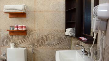 A bathroom with a sink, a toilet, a towel rack, a hairdryer, and a shelf with toiletries.