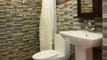 A bathroom with a toilet, shower, and sink.