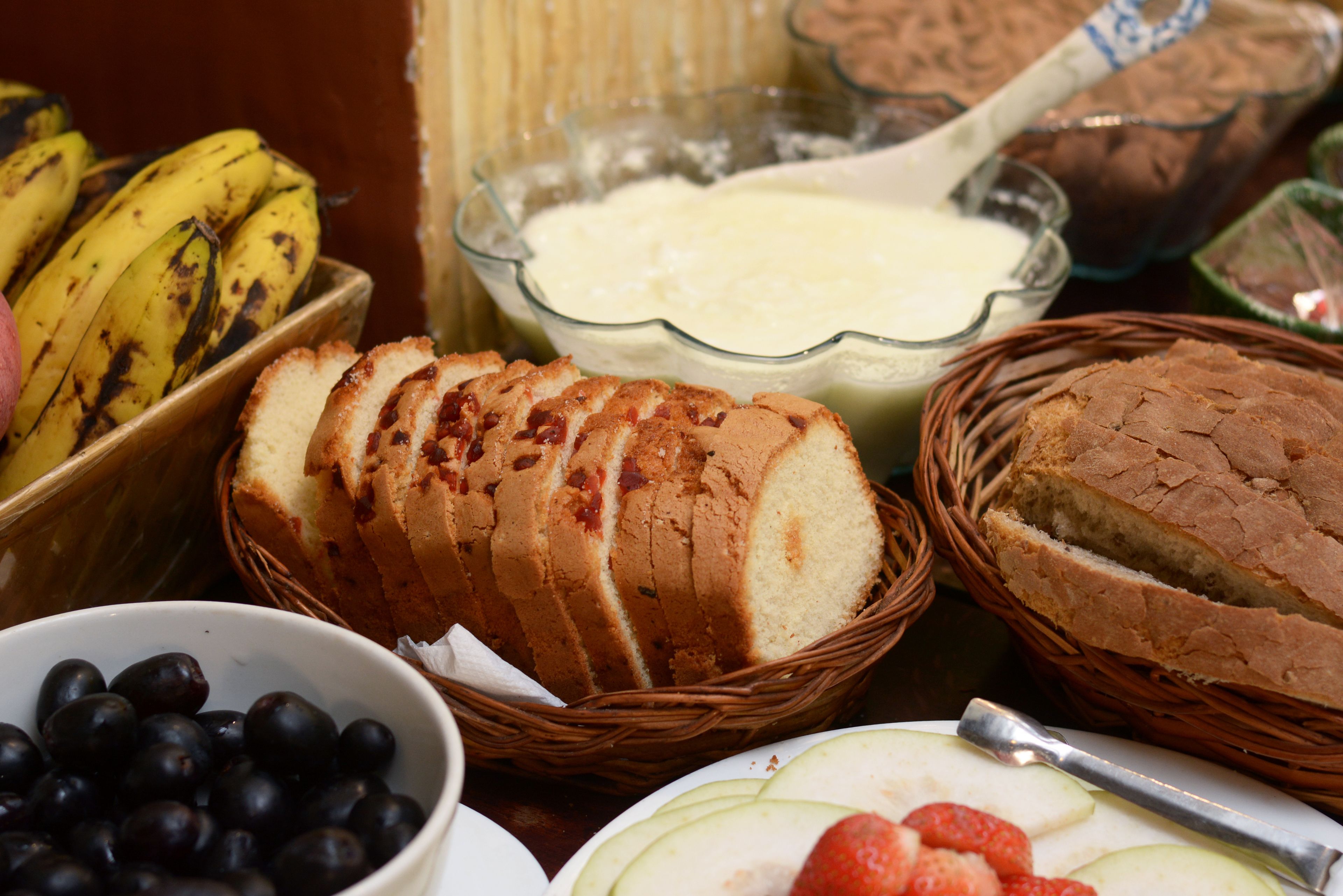 A table with various food items including bread, bananas, apples, and berries.