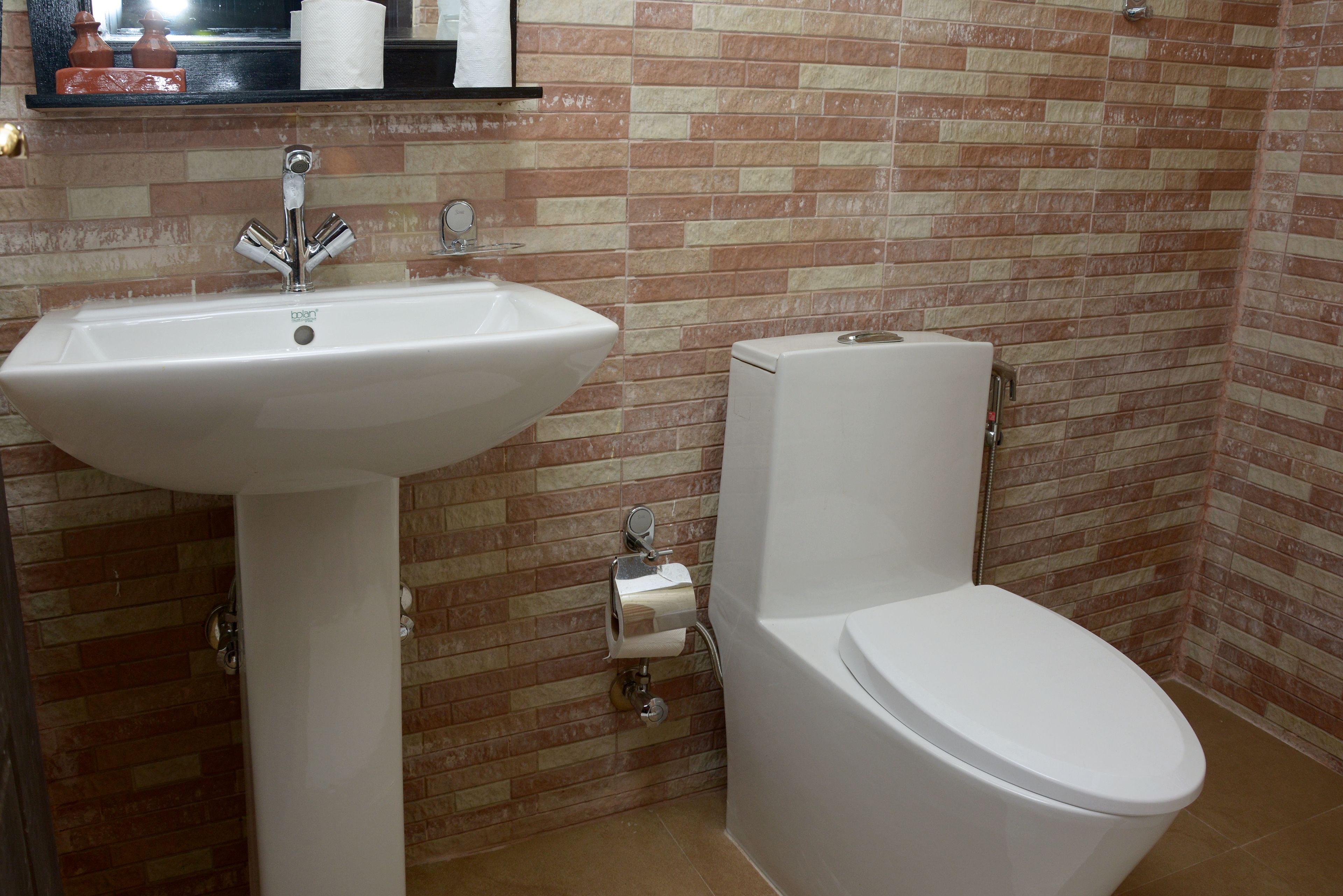 Um banheiro com pia branca, vaso sanitário e suporte para papel higiênico na parede.