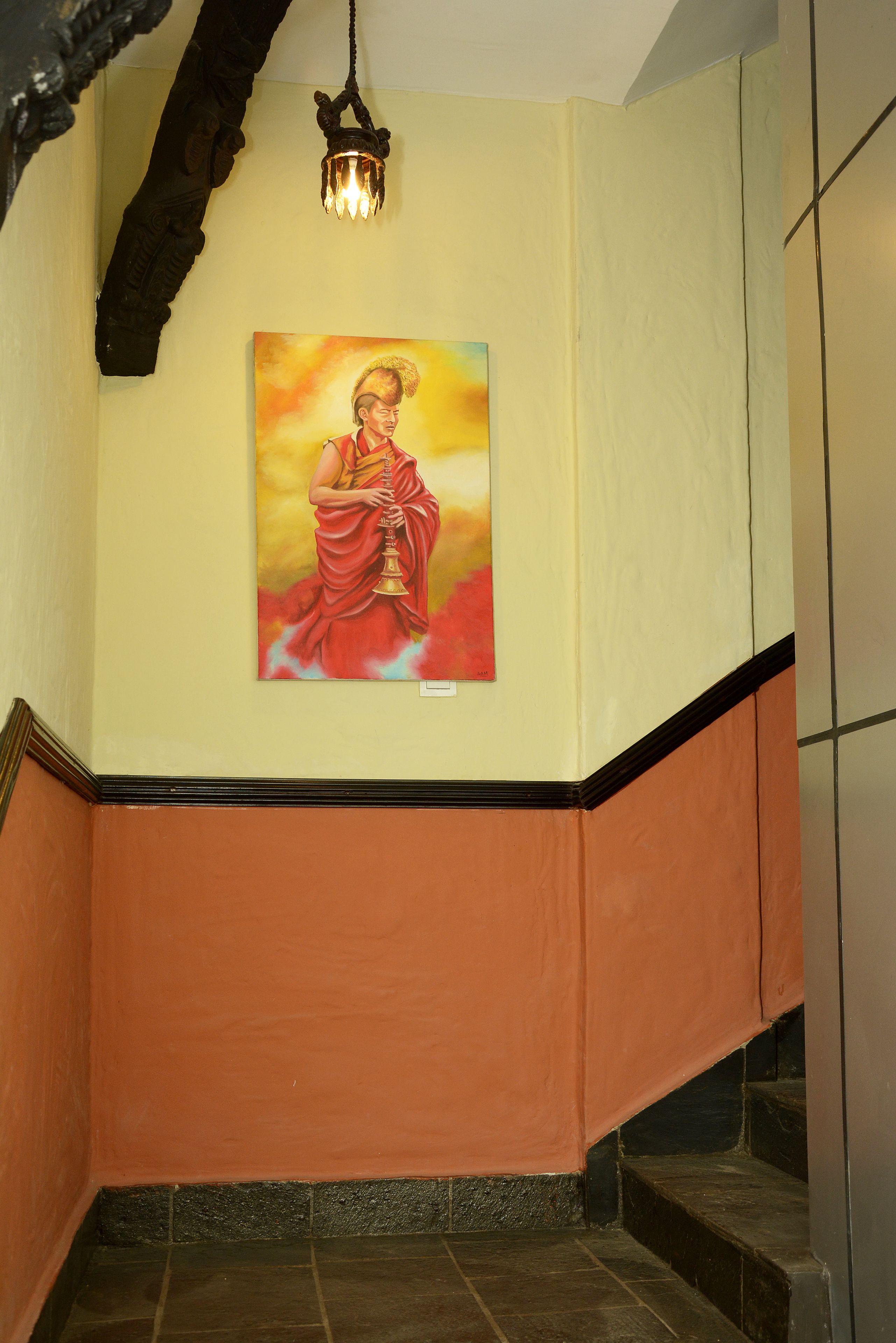 Un escalier orné d’un tableau représentant une figure en rouge, un luminaire et un mur à motifs texturés.
