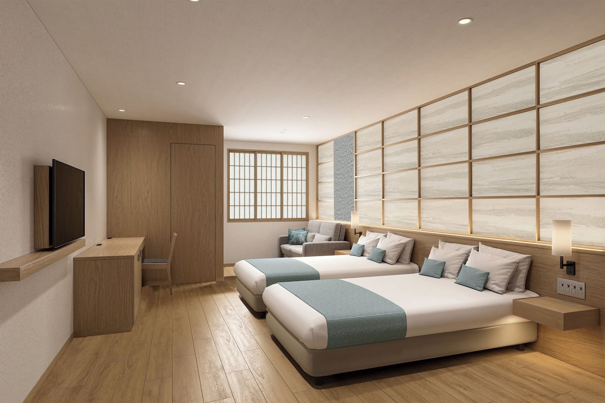 A modern hotel room with a large bed, bedside tables, a TV, and a view of the city.