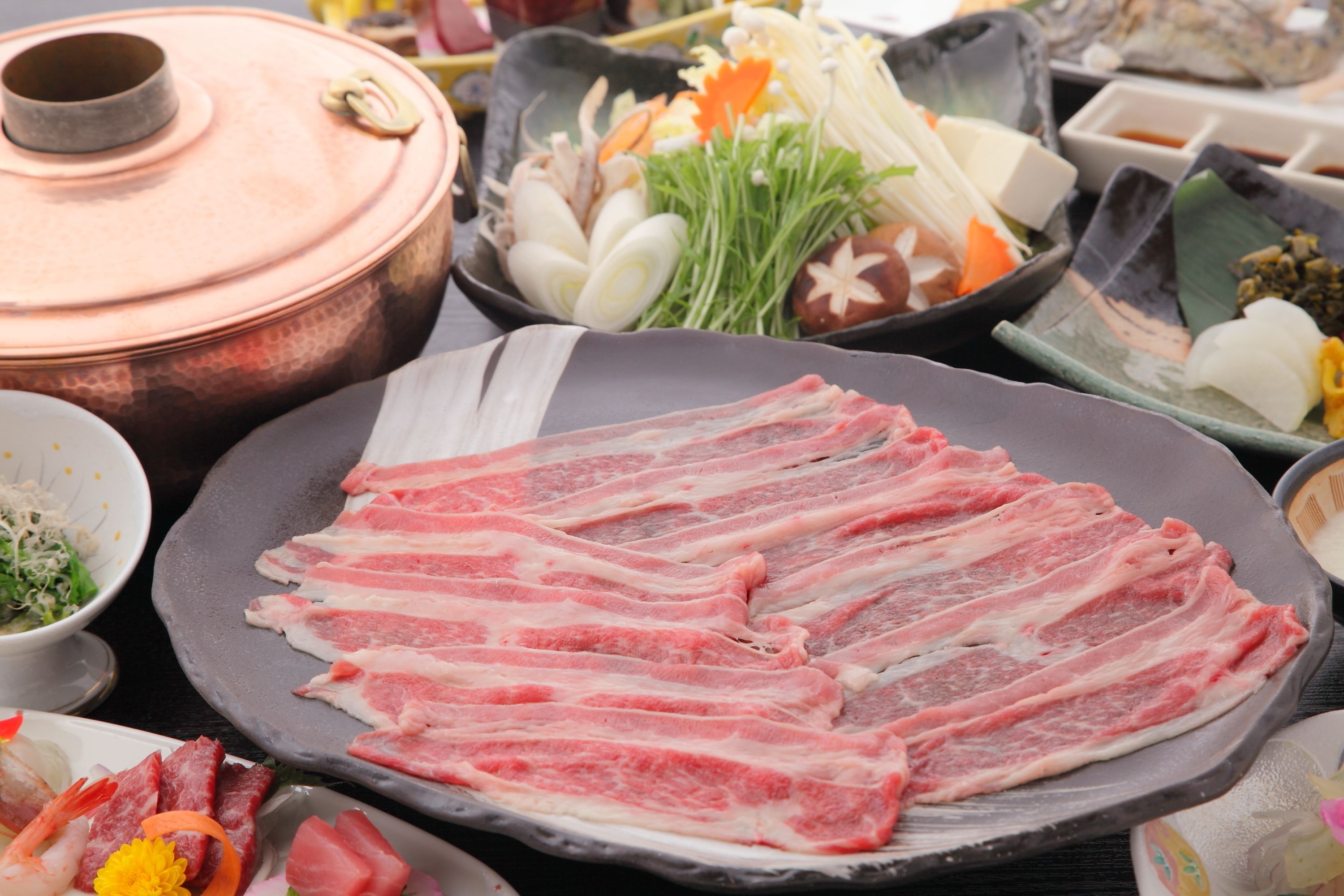 A table with various food items including raw fish, vegetables, and sauces.