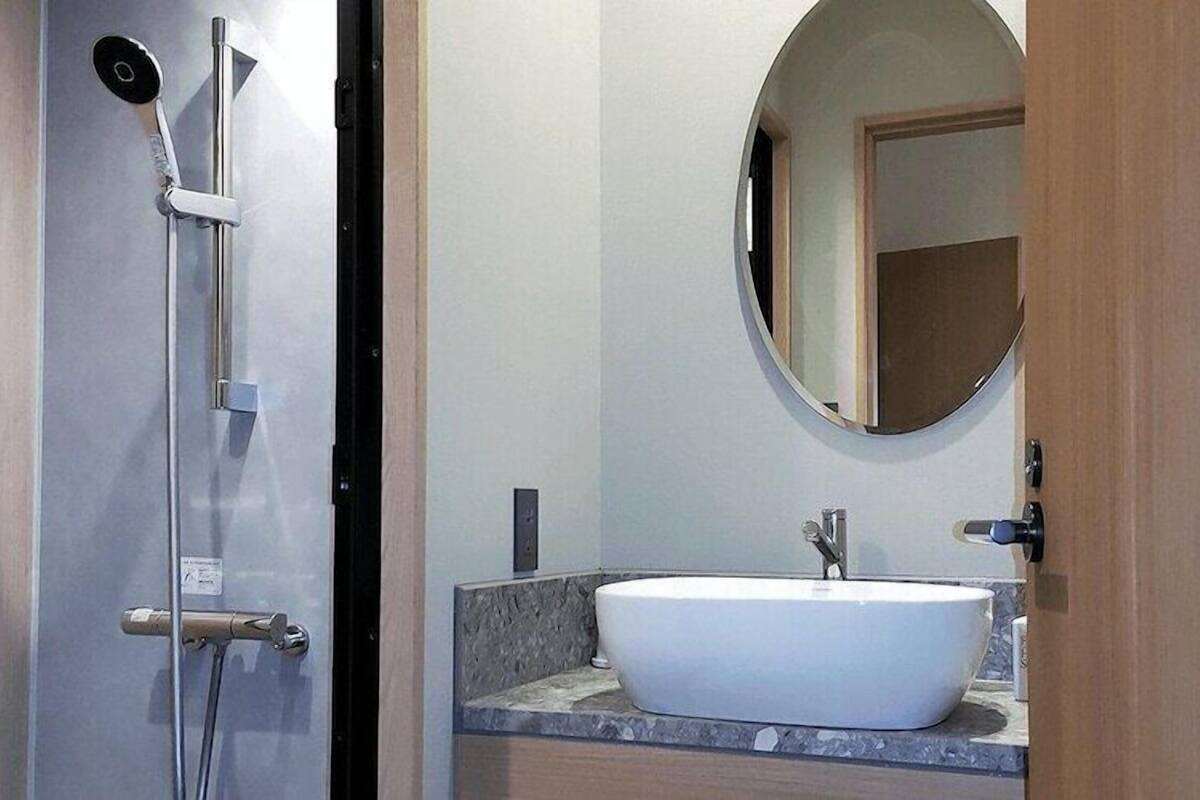 A bathroom with a shower, a sink, and a mirror.