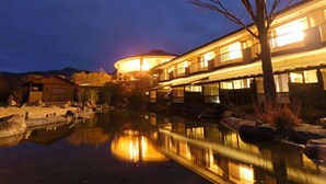 A building with a reflective water body in front, a tree, and a mountain in the background.