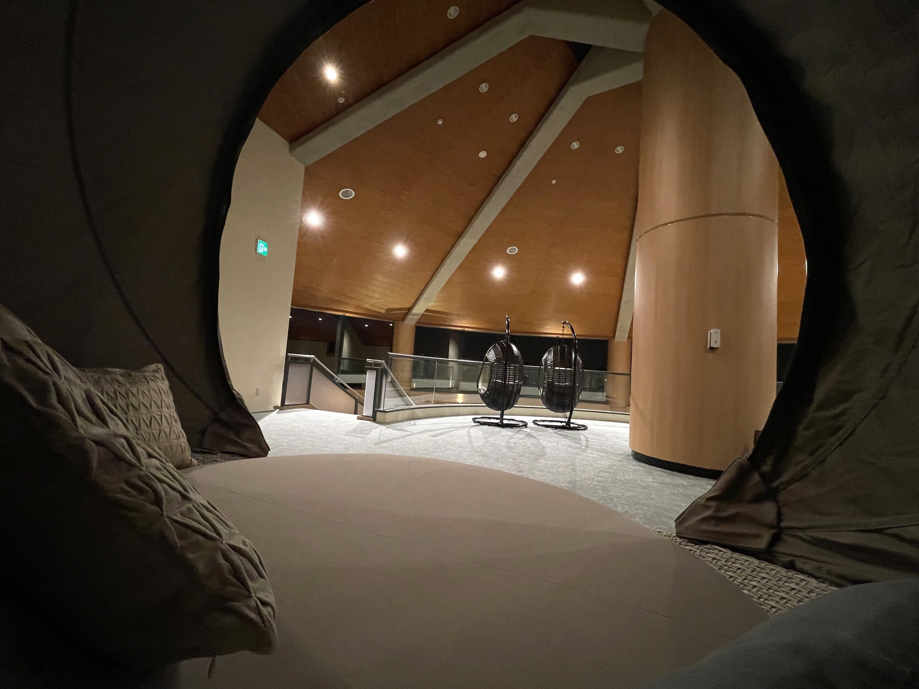 A modern interior with a high ceiling, circular windows, and a central staircase.