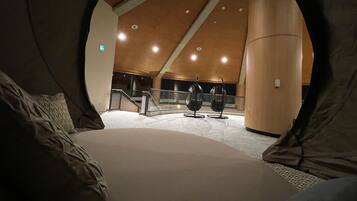 A modern interior with a high ceiling, circular windows, and a central staircase.