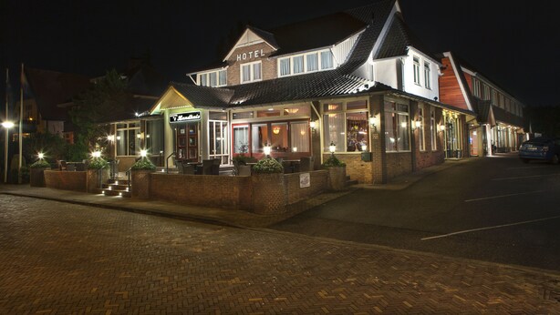 Een hotel in traditionele bouwstijl, met een groot 'HOTEL' bord boven de ingang.