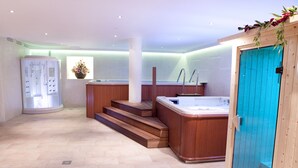 Een wellnessruimte met een houten bad, een sauna en een massagetafel.
