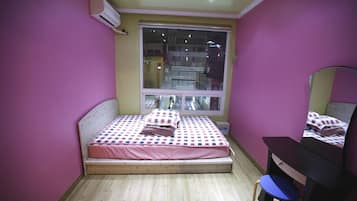 A bedroom with a bed, a desk, and a window.