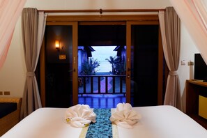 Une chambre d’hôtel avec un lit, une vue sur la mer par une porte ouverte et un balcon avec une balustrade.
