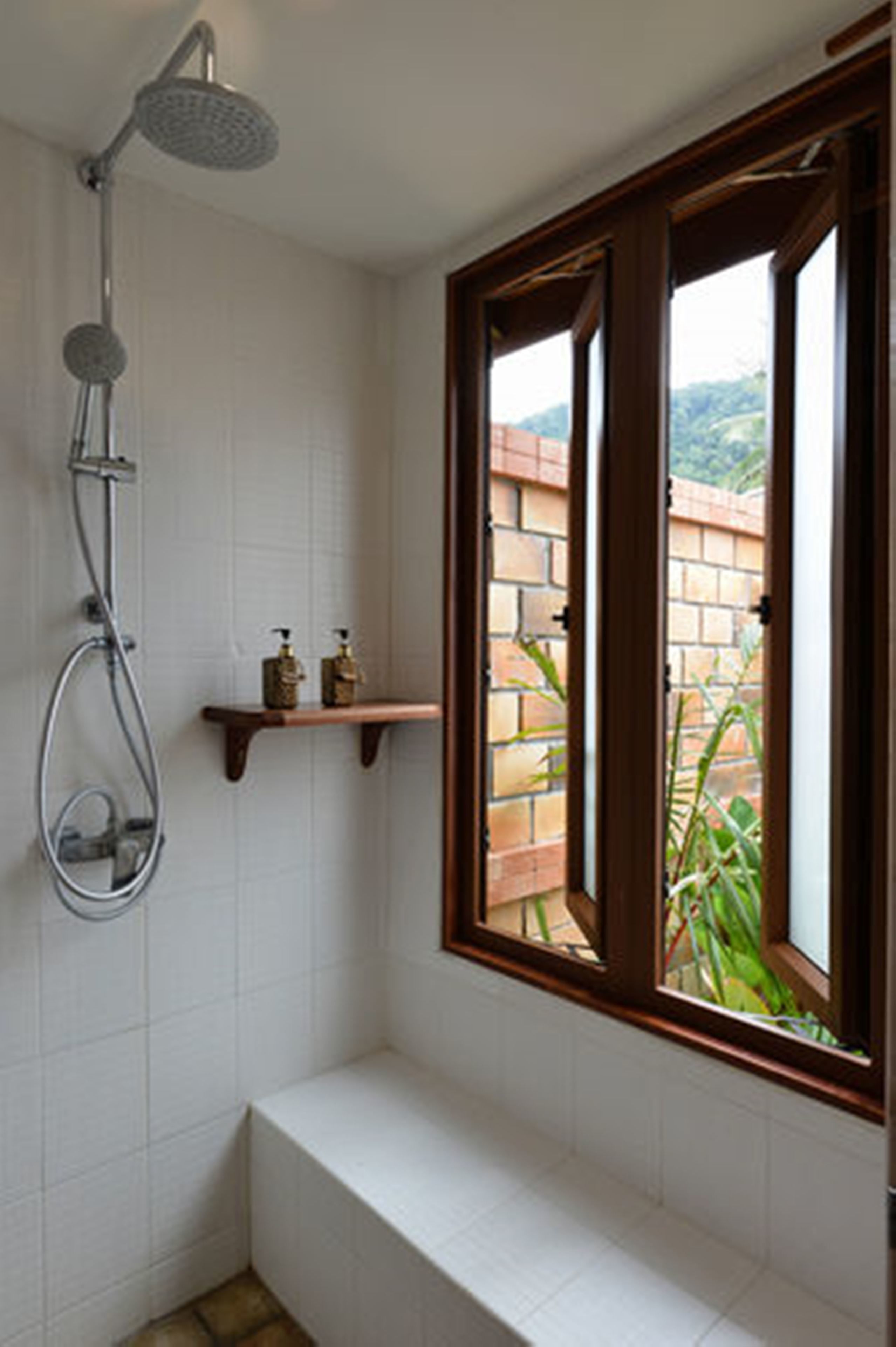 Un baño con ducha, una ventana y un estante con artículos de aseo.