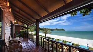 Une terrasse en bois avec des sièges, donnant sur une plage et l’océan.