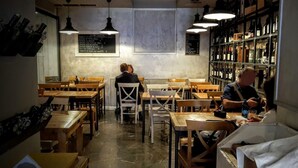 L’intérieur d’un restaurant avec des tables et des chaises en bois, des luminaires suspendus et un meuble à vin.