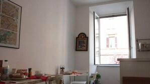 A small dining area with a table, chairs, and a window with a view of a building. - Scipione B&B (Rome)